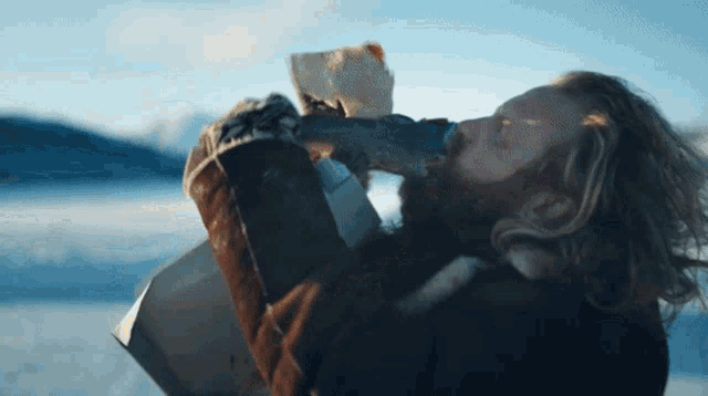 a man with a beard is drinking from a cup in the snow