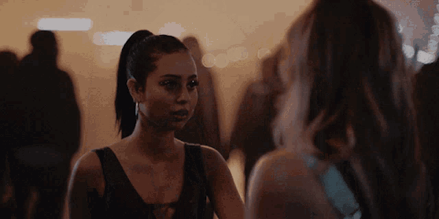 two women are looking at each other in a crowded area