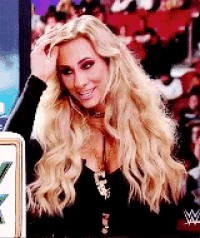 a woman with long blonde hair is smiling and holding her head