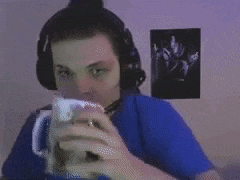 a man wearing headphones and a blue shirt is holding a coffee mug