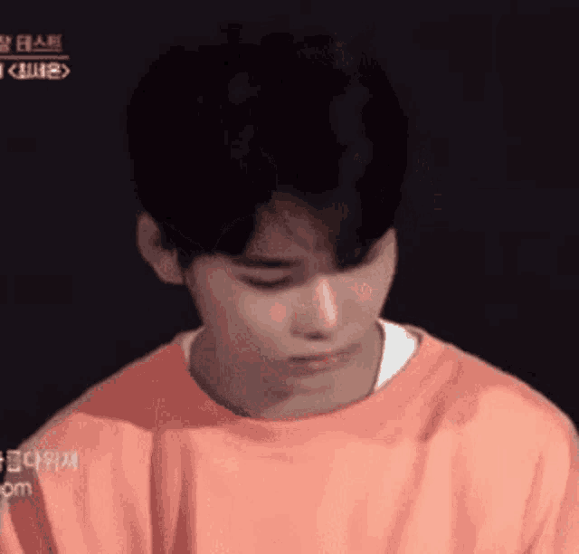 a close up of a young man wearing an orange sweatshirt .