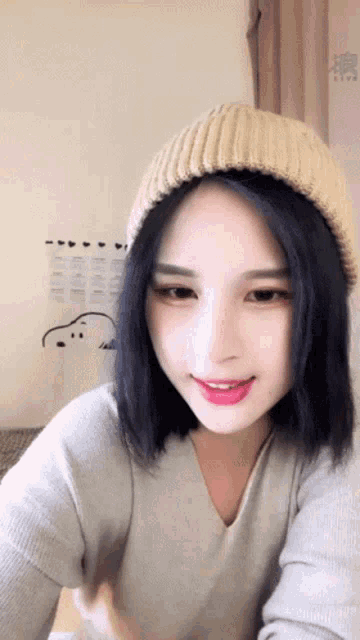 a woman wearing a beanie and a sweater is smiling
