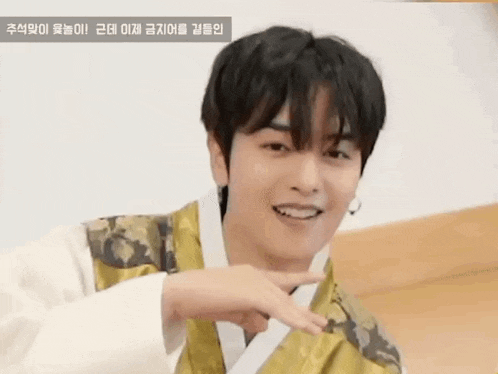 a young man in a kimono is smiling and making a face .