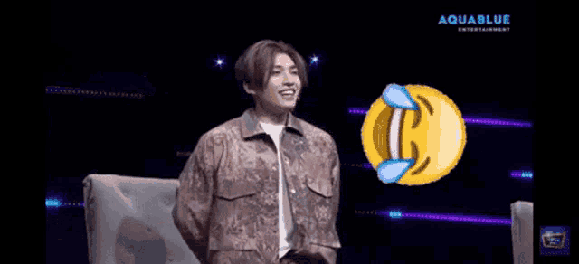a man is sitting in a chair laughing with a smiley face in front of him that says aquablue entertainment