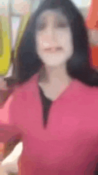 a blurry picture of a woman wearing a pink sweater and a black shirt .