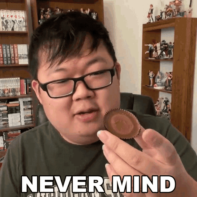 a man with glasses is holding a peanut butter cup with the words never mind written on it