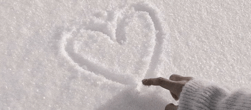 a person is writing a heart in the snow .
