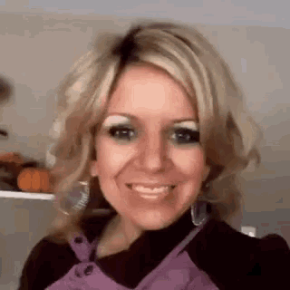 a close up of a woman wearing a purple apron and earrings smiling .