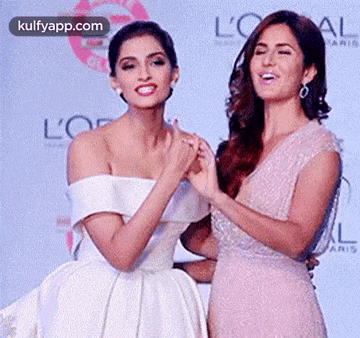 two women are standing next to each other on a red carpet and holding hands .