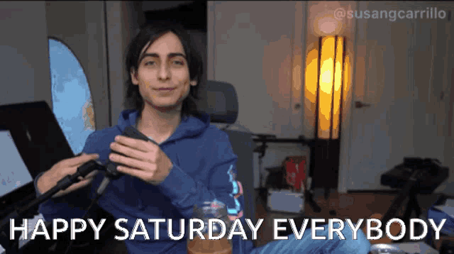a man in a blue hoodie says happy saturday everybody on the screen