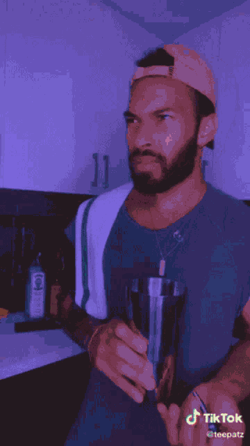 a man in a kitchen with a bottle of bombay sapphire next to him