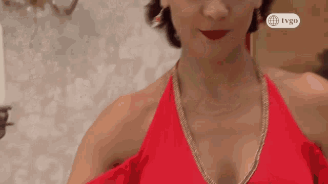 a woman in a red dress is standing in front of a white wall .