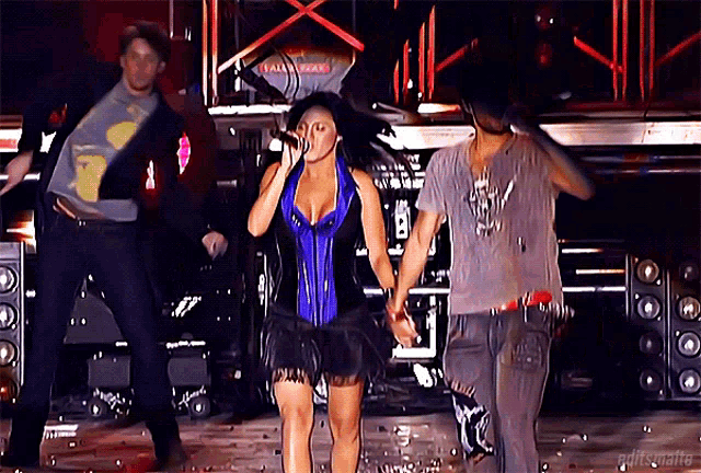 a woman in a blue corset singing into a microphone on a stage