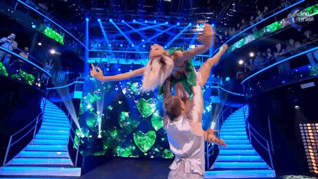 a woman is being lifted in the air by a man on a stage with the words dancing on it