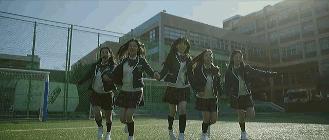 a group of girls in school uniforms are running in a field