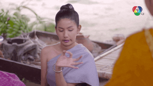 a woman in a purple dress is making a hand gesture with the number 7 in the background
