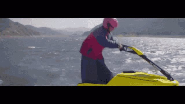 a man in a pink helmet is riding a jet ski