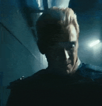 a man with blonde hair is standing in a dark room .