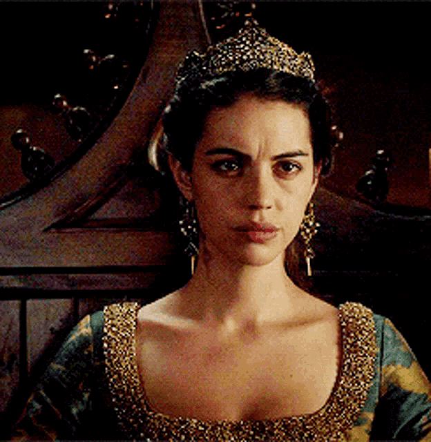 a woman wearing a tiara and earrings is sitting on a throne