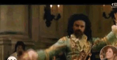 a man in a green and gold costume is dancing in a room with candles .