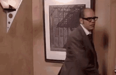 a man in a suit and glasses is standing in front of a door .