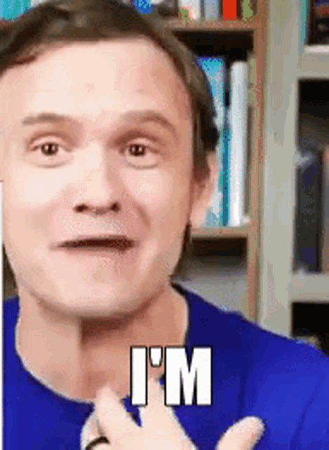 a man in a blue shirt is making a funny face and says i 'm