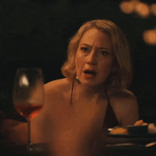 a woman is sitting at a table with a glass of wine in front of her