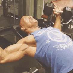 a man in a blue tank top is lifting a dumbbell