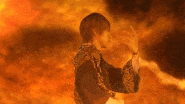 a man in a kimono is standing in front of a fire