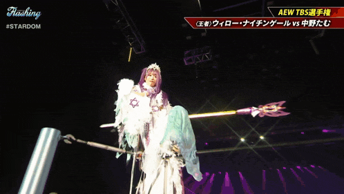 a woman in a white feathered costume is holding a spear in front of a sign that says " stardom "