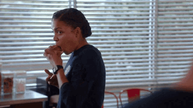 a woman with a watch on her wrist is eating a sandwich