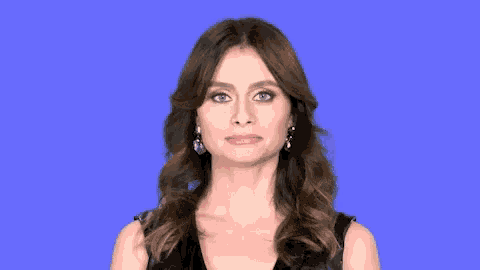 a woman wearing earrings and a black dress makes a funny face