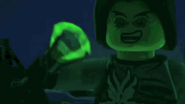 a glow in the dark lego figure is holding a green object in his hand .