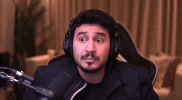 a man wearing headphones is sitting in front of a microphone making a funny face .