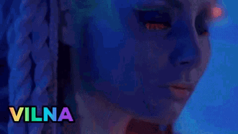 a woman is sitting on a table in front of a blue wall with vilna written on the bottom