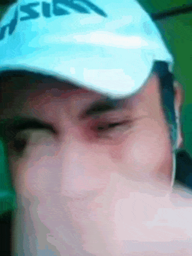 a close up of a man wearing a hat that says ' asics ' on it