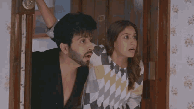 a man and a woman are standing in a doorway looking at something