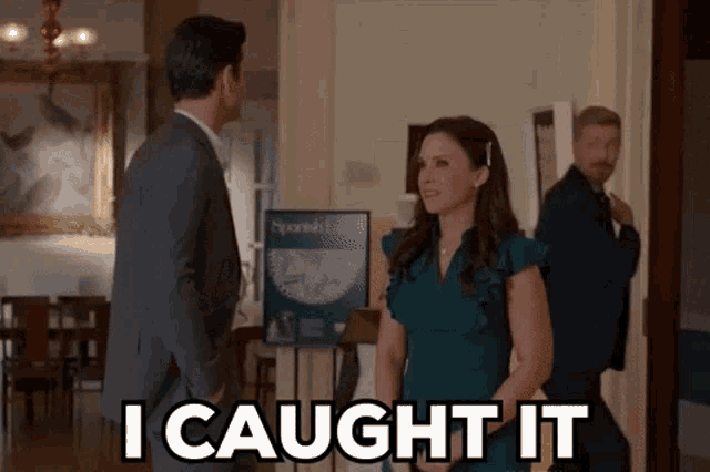 a woman in a green dress is standing next to a man in a suit and says i caught it .