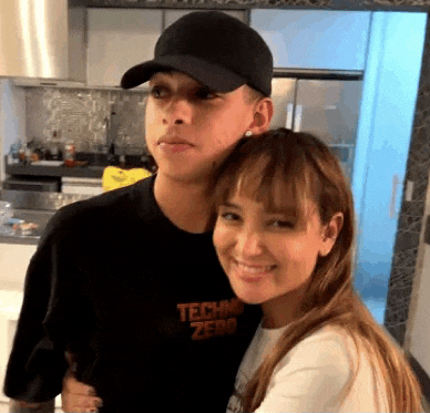 a man and a woman are posing for a picture in a kitchen .