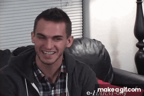 a man sitting on a couch with a make a gif.com watermark on the bottom right