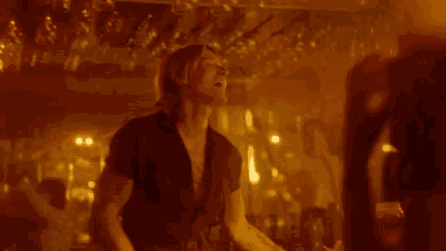 a man is playing a guitar in a dark room and talking to a woman .