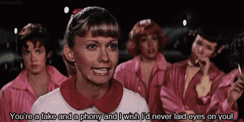 a woman in a white shirt with a red collar is talking to a group of girls in pink jackets