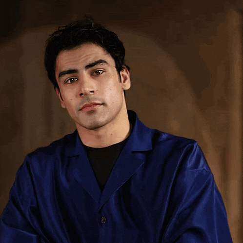 a man wearing a blue jacket and black shirt looks to the side