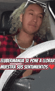 a man in a plaid shirt is crying while sitting in the driver 's seat