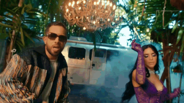 a man and a woman are dancing in front of a camper van