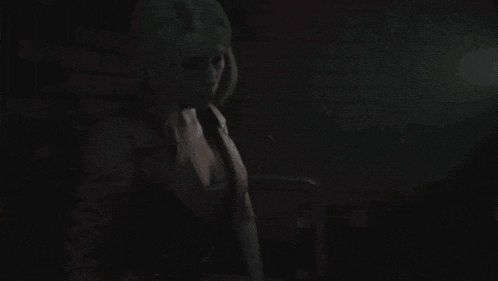 a woman in a dark room with a brick wall in the background