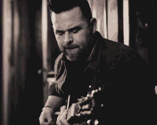 a black and white photo of a man playing a guitar