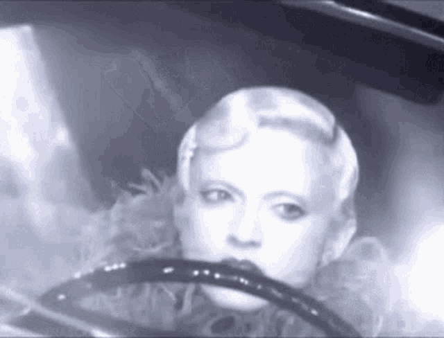 a woman is sitting in a car with a steering wheel .