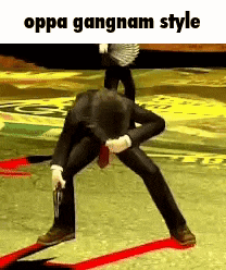 a man in a suit and tie is holding a gun and kneeling down on the ground .