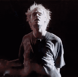 a man is singing into a microphone while holding his arm in the air .
